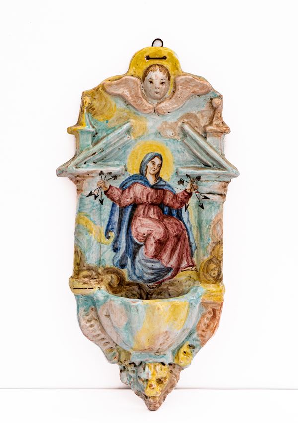 Manifattura di Cerreto Sannita del XIX secolo - Acquasantiera con effigie della Madonna delle Grazie recante in mano delle frecce spezzate, incorniciata da motivi architettonici e la testa di un cherubino a rilievo 