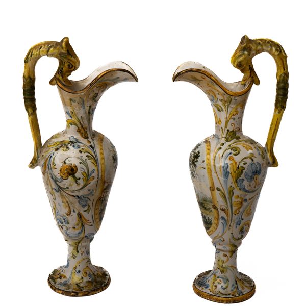 Manifattura del Centro Italia della fine del XIX secolo - Coppia di piccoli versatoi in maiolica con decoro a girali fogliati e con paesaggi nelle riserve, anse a foggia di animale fantastico