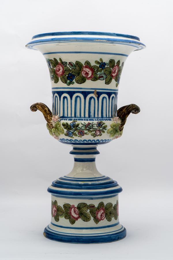 Manifattura napoletana della fine del XIX secolo - Vaso a cratere Medici in maiolica dipinta con motivi geometrici azzurri e serti di roselline.