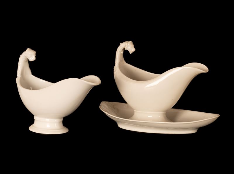 Coppia di salsiere in porcellana bianca di gusto neoclassico con decori a rilievo e prese termina...
